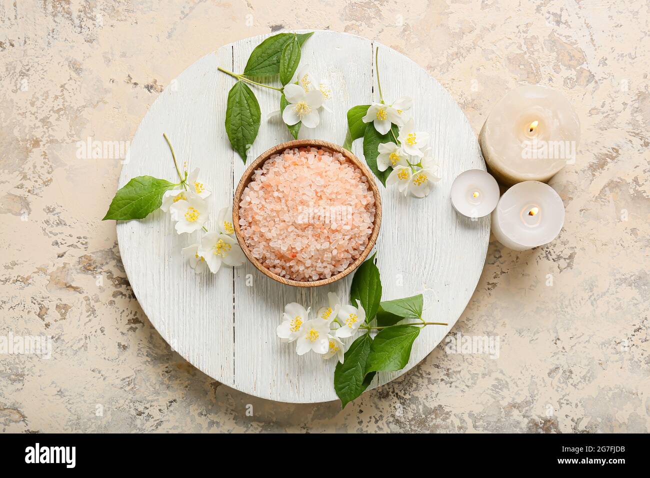 Tray with sea salt, burning candles and jasmine flowers on grunge background Stock Photo