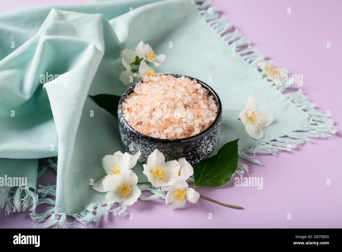 Composition with bowl of sea salt and jasmine flowers on color background Stock Photo