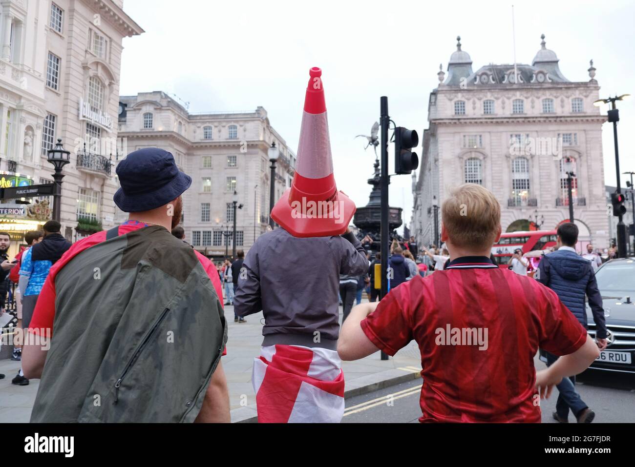 England football fans, one wearing a traffic cone on his head walk around London's West End after Euro 2020 victory against Germany. Stock Photo
