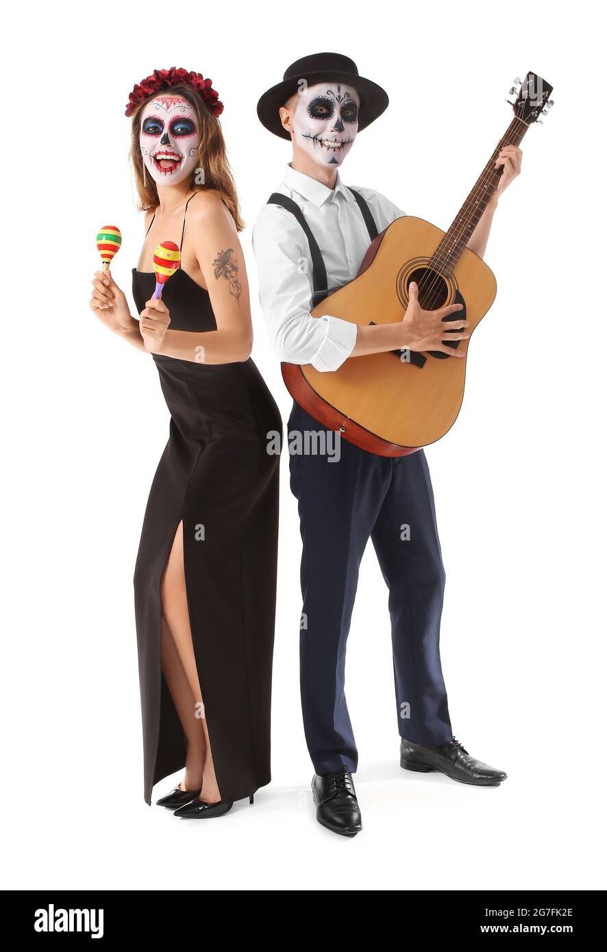 Young couple with painted skull on faces, maracas and guitar against white background. Celebration of Mexico's Day of the Dead (El Dia de Muertos) Stock Photo