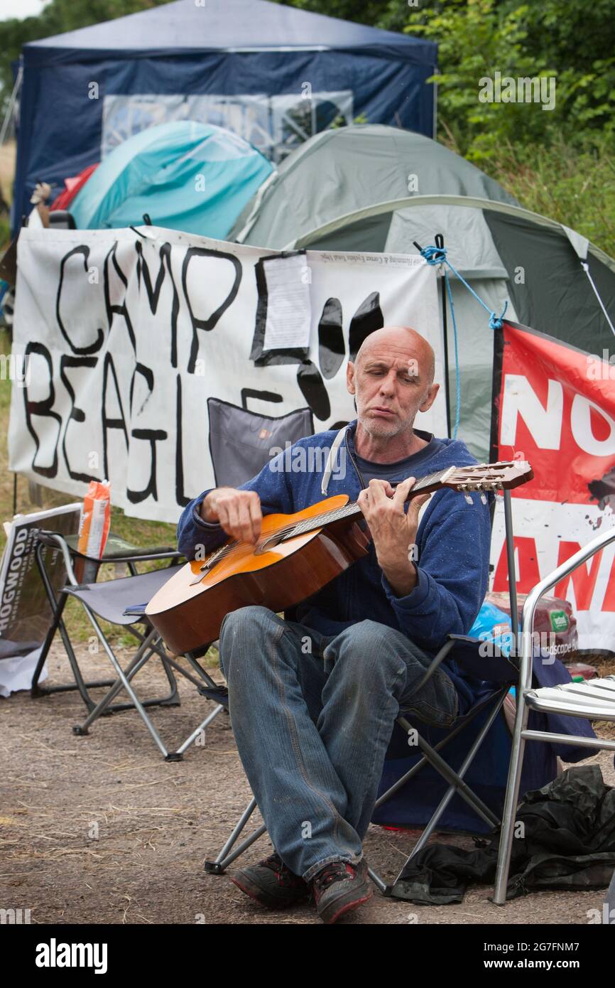 Huntingdon, UK. 13th July, 2021. An activist plays a guitar near the tents  and placards during the demonstration.Animal rights activists occupy Camp  Beagle, a protest camp on the roadside outside beagle breeder