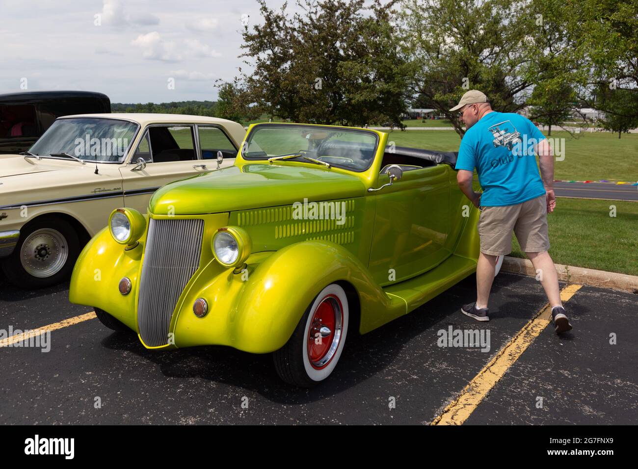 A man inspects a chartreus yellow 1936 Ford Cabriolet roadster on display at a car show in Angola, Indiana, USA. Stock Photo