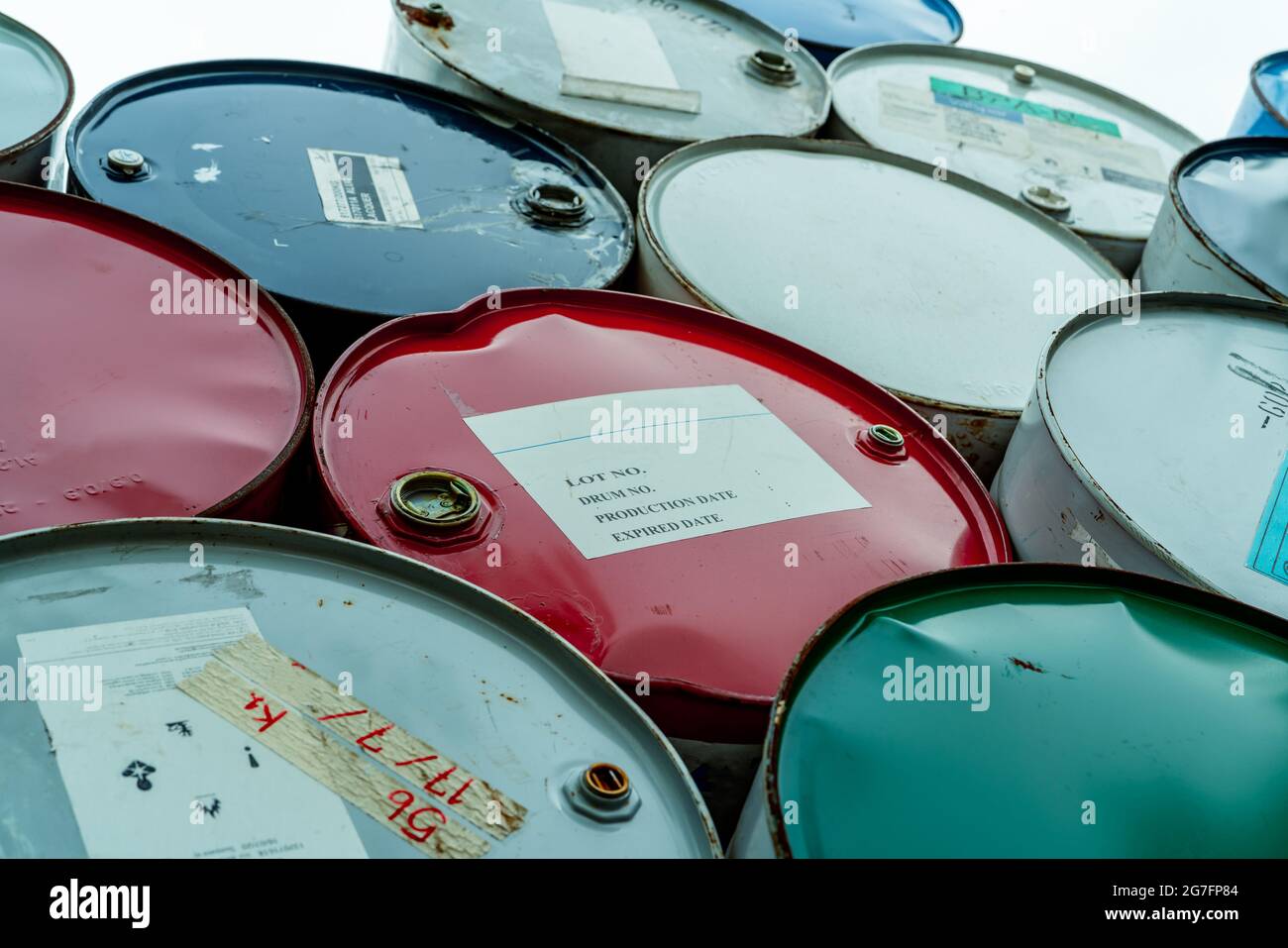 Old chemical barrels stack. Red, green, and blue chemical drum. Steel tank of flammable liquid. Hazard chemical barrel. Industrial waste. Stock Photo