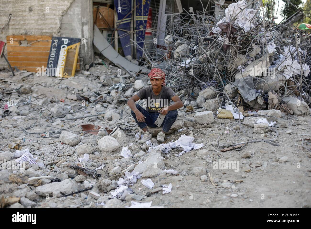 A Palestinian man sits on the rubble of a destroyed house after 11 days ...