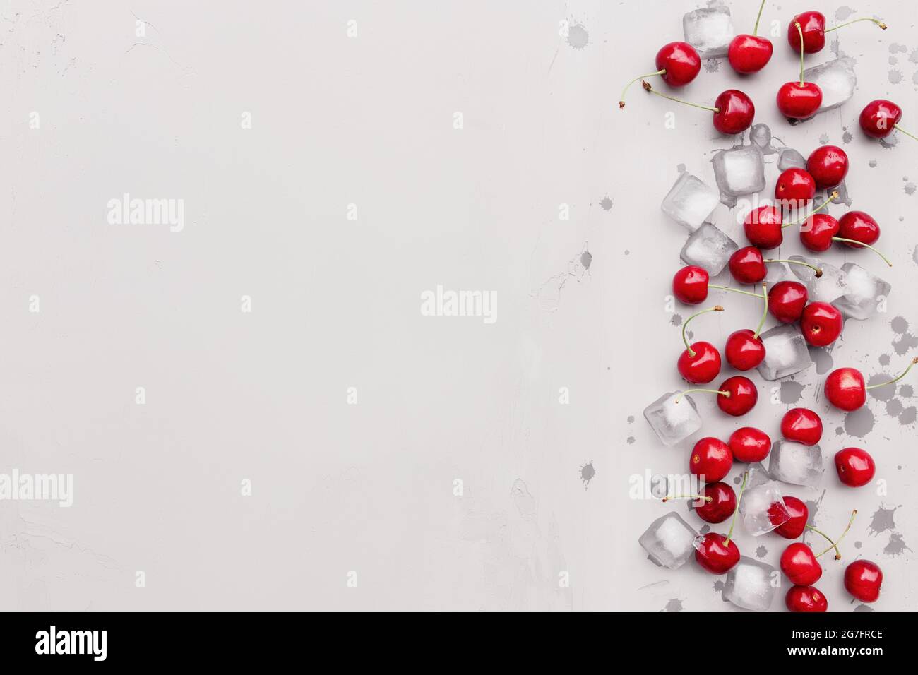 Flat lay top view on gray concrete background with sweet cherry berries and ice cubes. Freshness, summer conceptual minimal background. Eco, bio farm Stock Photo