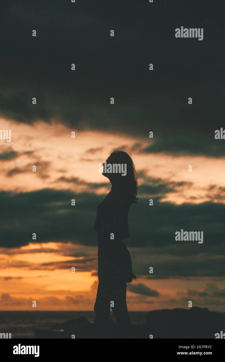 Girl silhouette with an ocean sunset sky background Stock Photo - Alamy