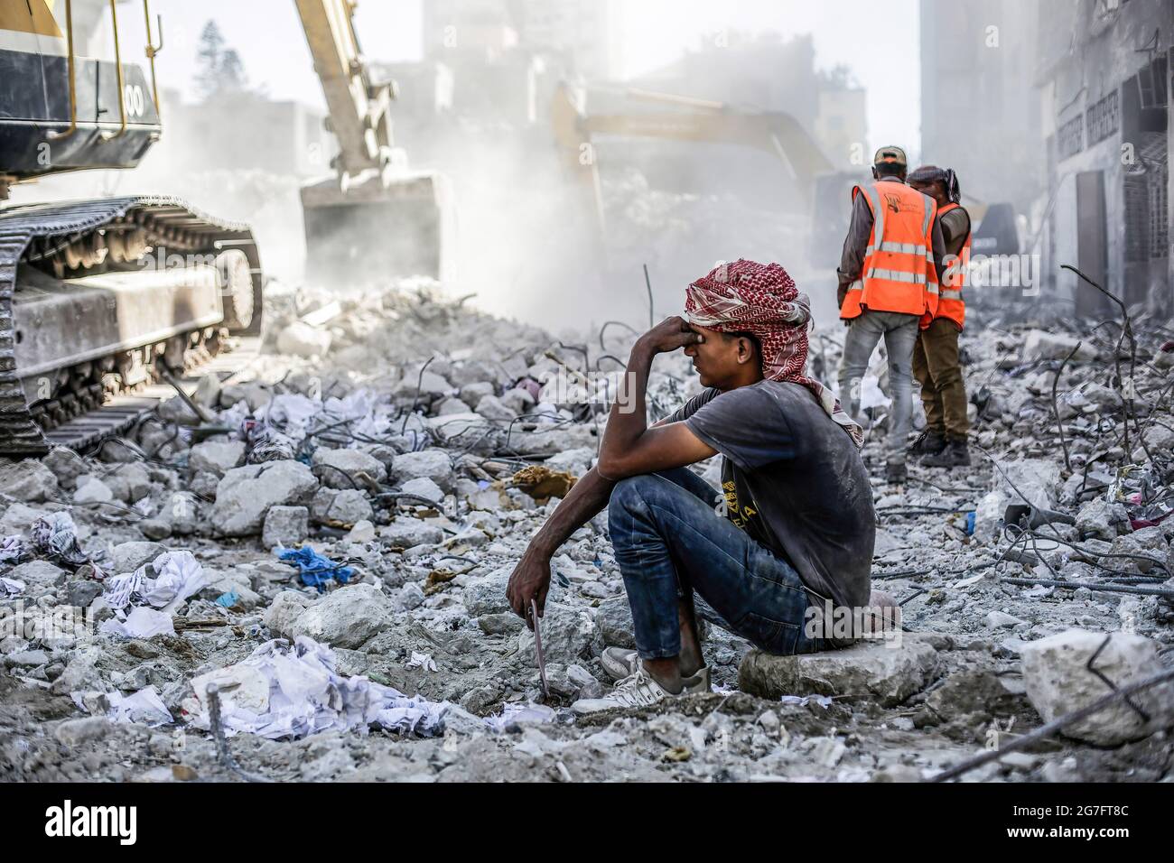A Palestinian man sits on the rubble of a destroyed house after 11 days ...