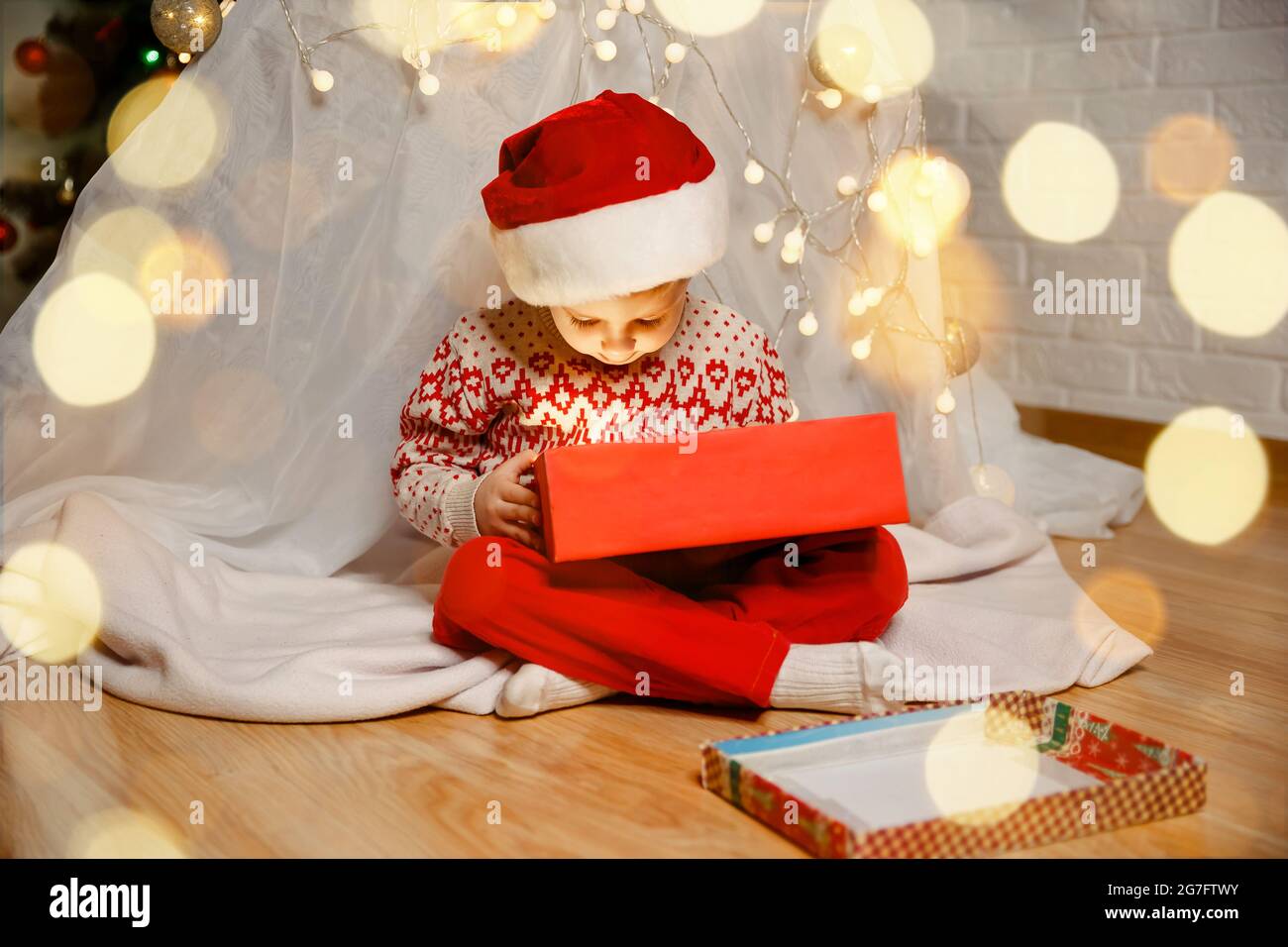 Child playing near Christmas tree. Family with gifts on Xmas eve Stock Photo