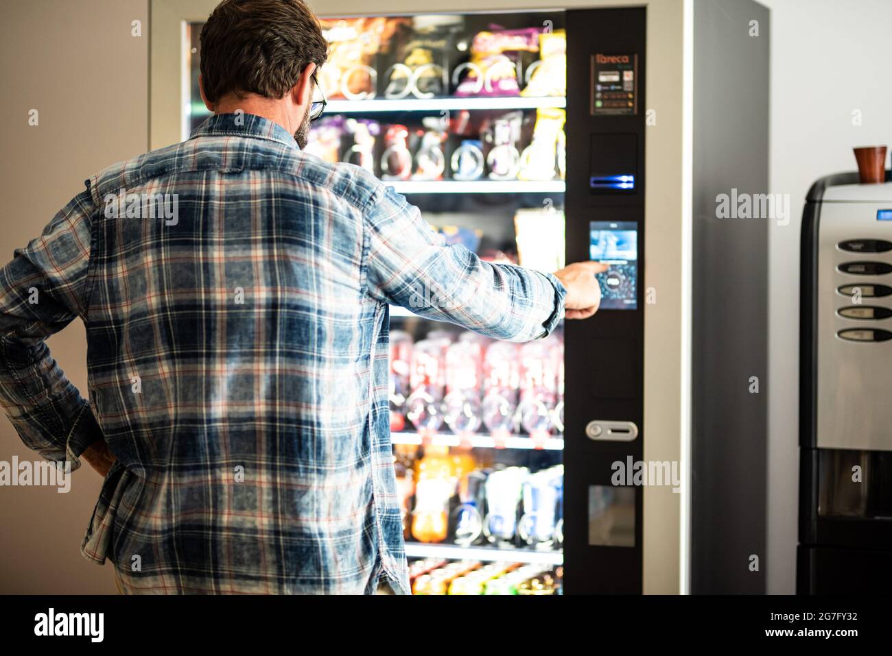 Back view of adult mature man choosing snacks and drinks on 24h free automated distributor - people buying food on airport gate - travel lifestyle and Stock Photo
