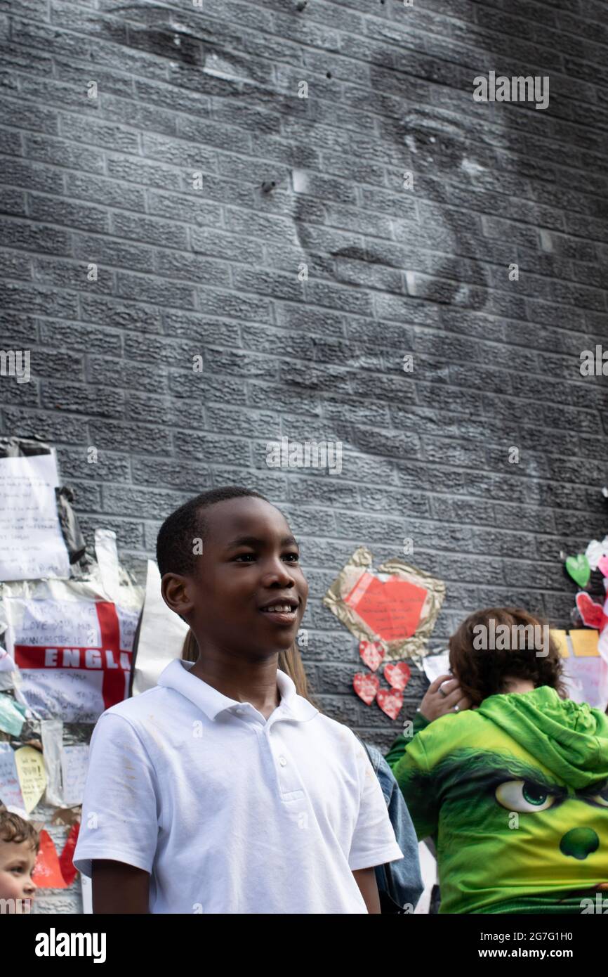 Marcus Rashford street art, Withington after repair by Akse P19. Boy standing in front of mural. Withington, Manchester UK Stock Photo