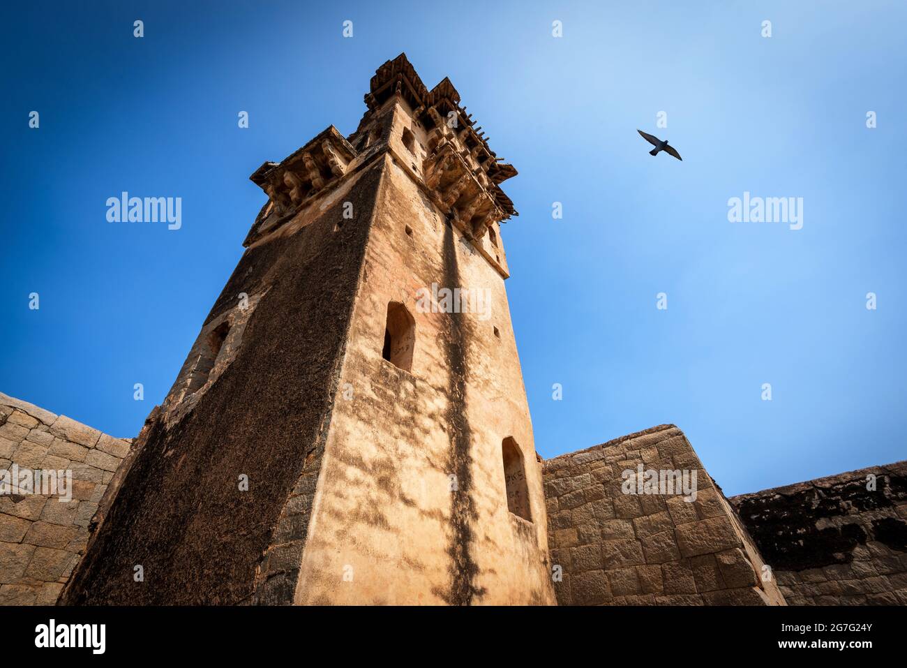 Zanana Enclosure. Base of demolished and disappeared Queens Palace with watch tower in back under blue cloudscape. Green foliage and grass. Hampi, Kar Stock Photo
