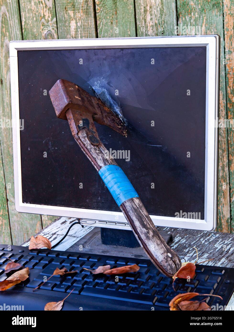 Axe in a Computer Screen Monitor on the Old Planks Background outdoor Stock Photo