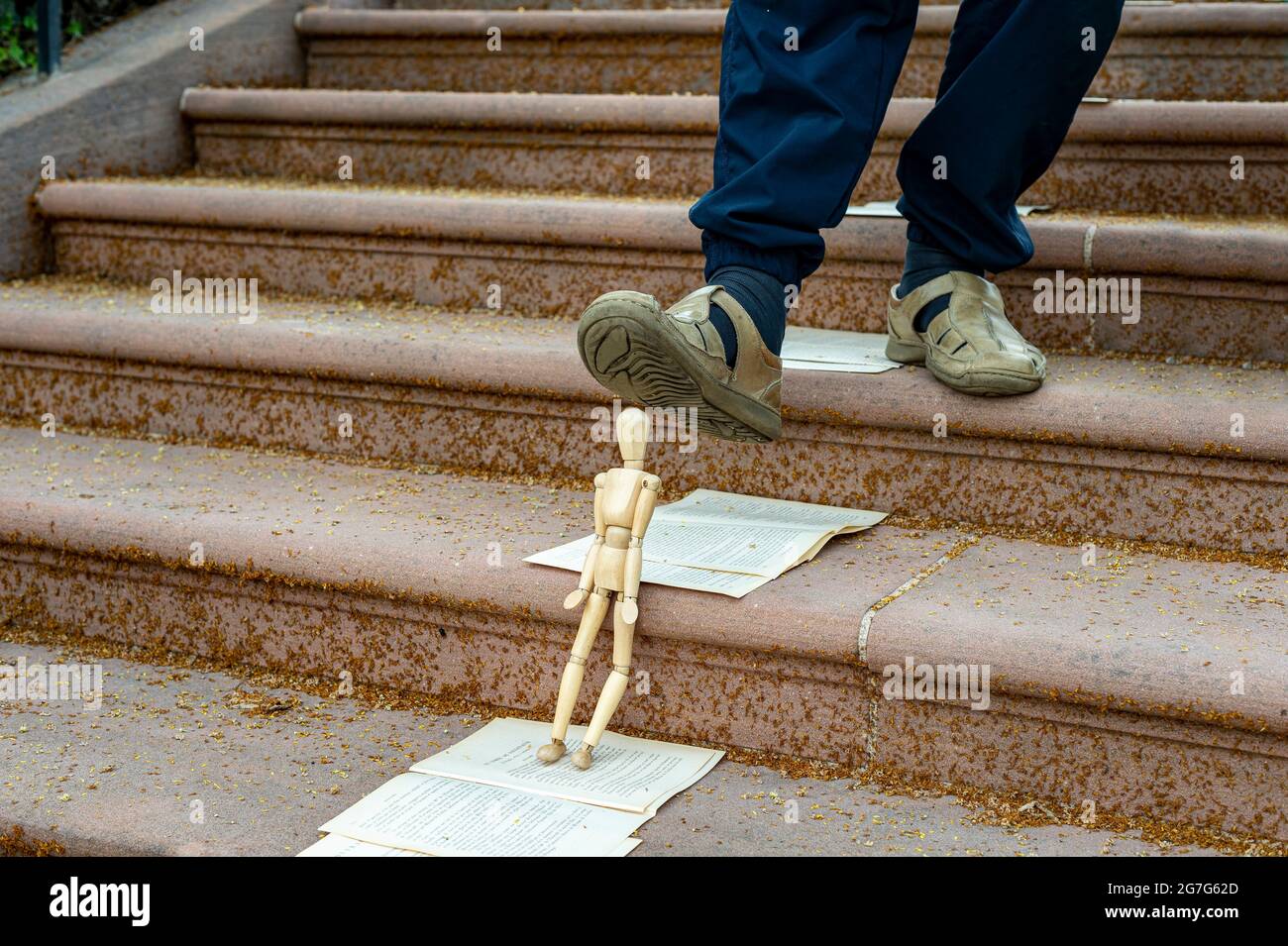 Puppet crushed by a foot in Haguenau, Alsace, France. The puppet leaning against a staircase step is under the foot of a person going down. Stock Photo