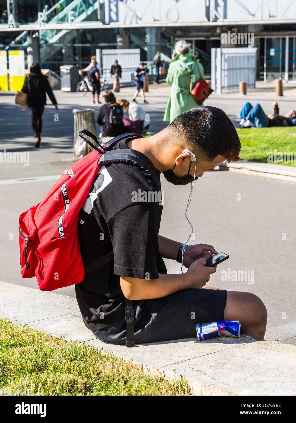 Young Asian man looking at telephone outside Montparnasse railway station - Paris, France. Stock Photo