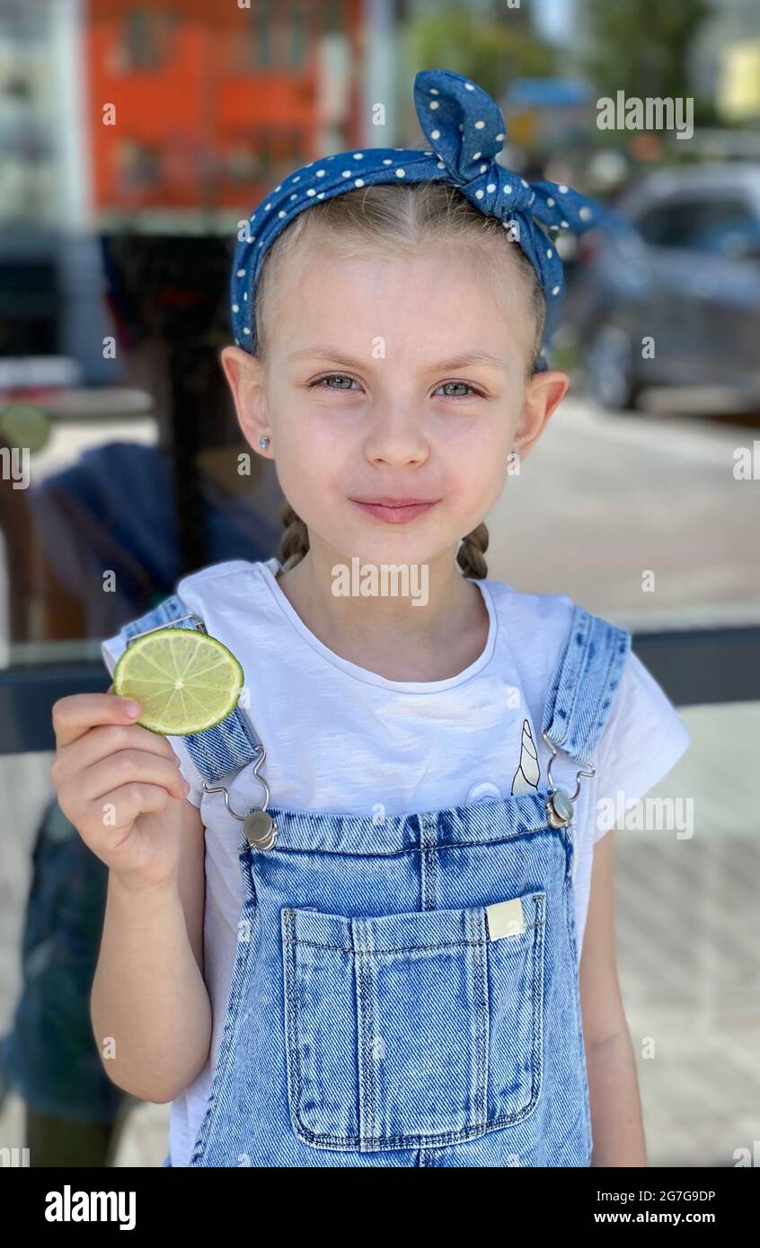Portrait of smiling cute little girl holding lime slices Stock Photo ...