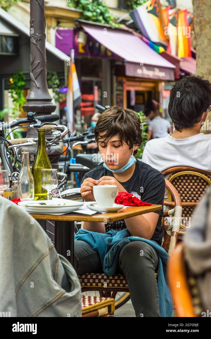 Young boy sat at outdoor restaurant table - Paris, France. Stock Photo