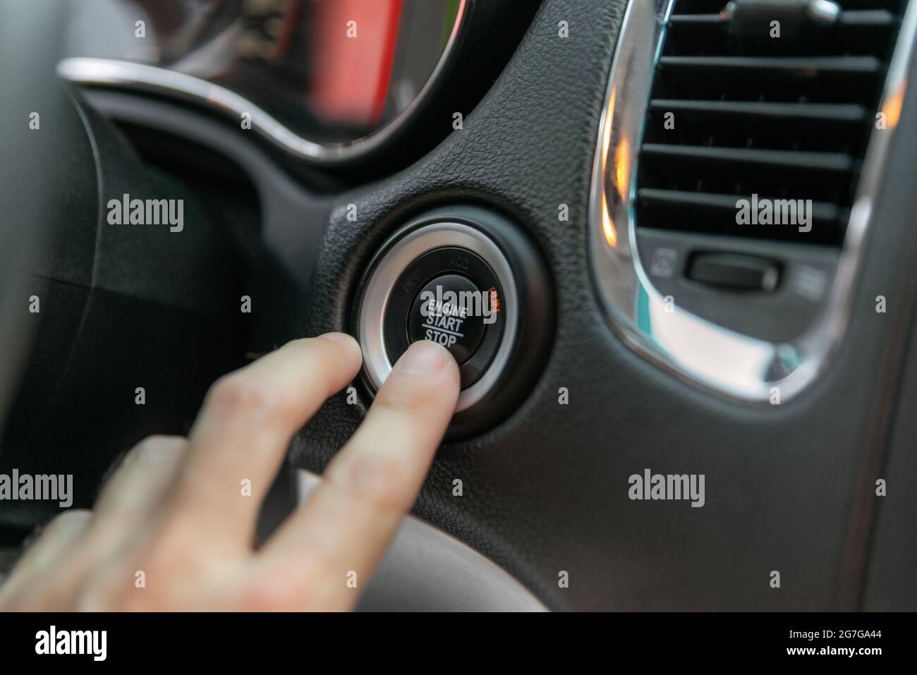 Male's finger pressing the start button, stop the engine in the luxury