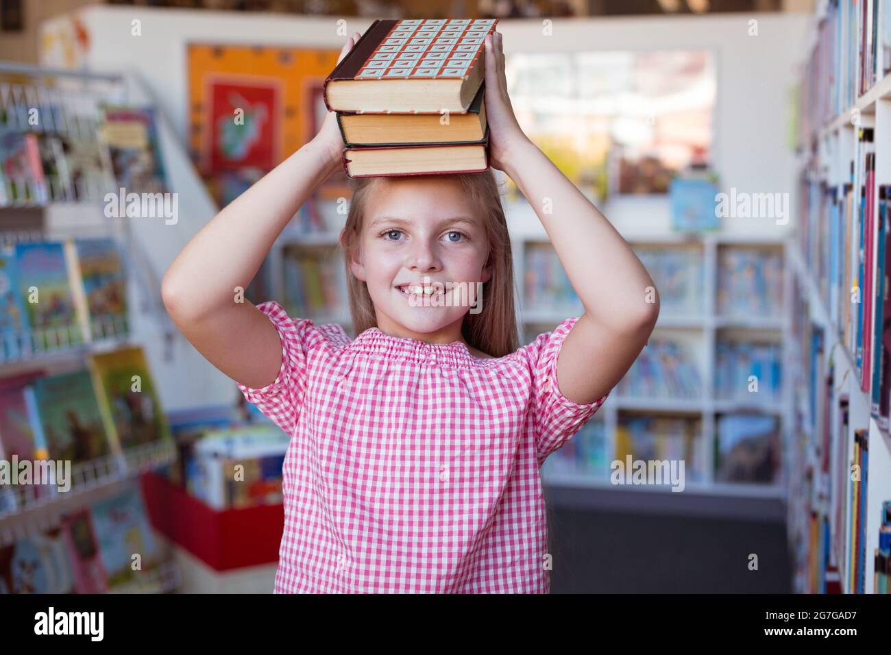 Portrait of caucasian schoolgirl smiling carrying stack of books on ...