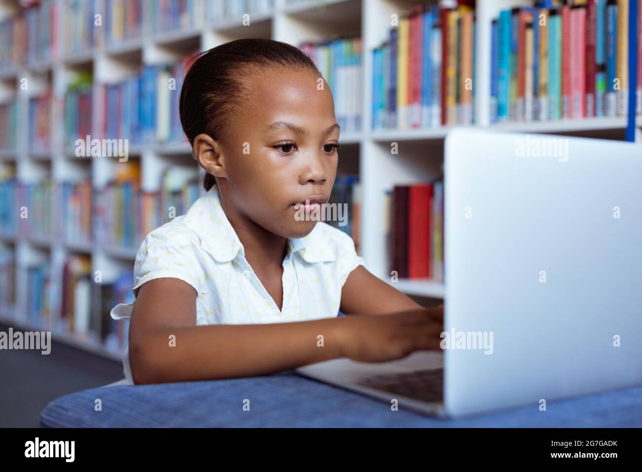 African american schoolgirl at desk in school library concentrating ...