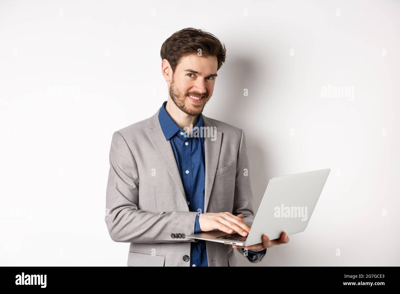 Successful smiling businessman working on laptop and looking happy at ...