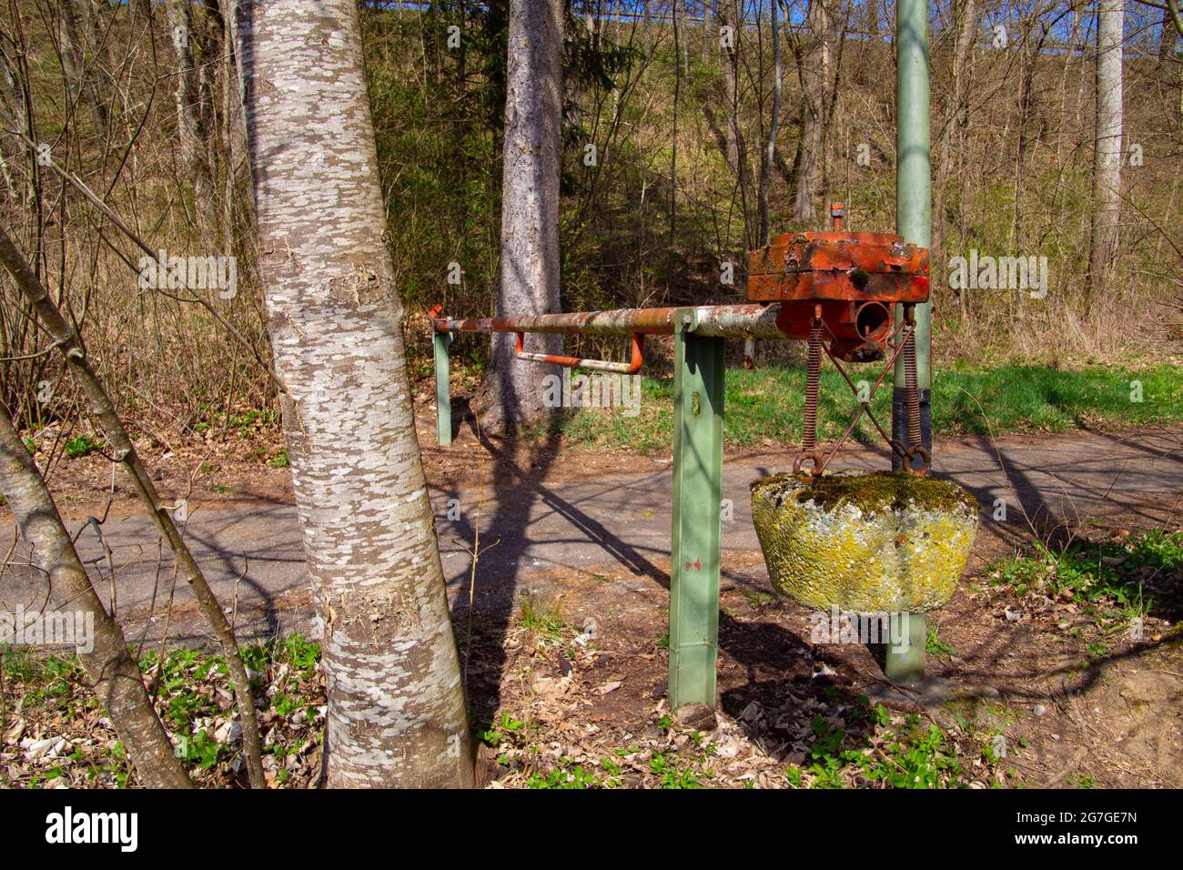 Old red and white manual operated lift barrier on a forest road with a