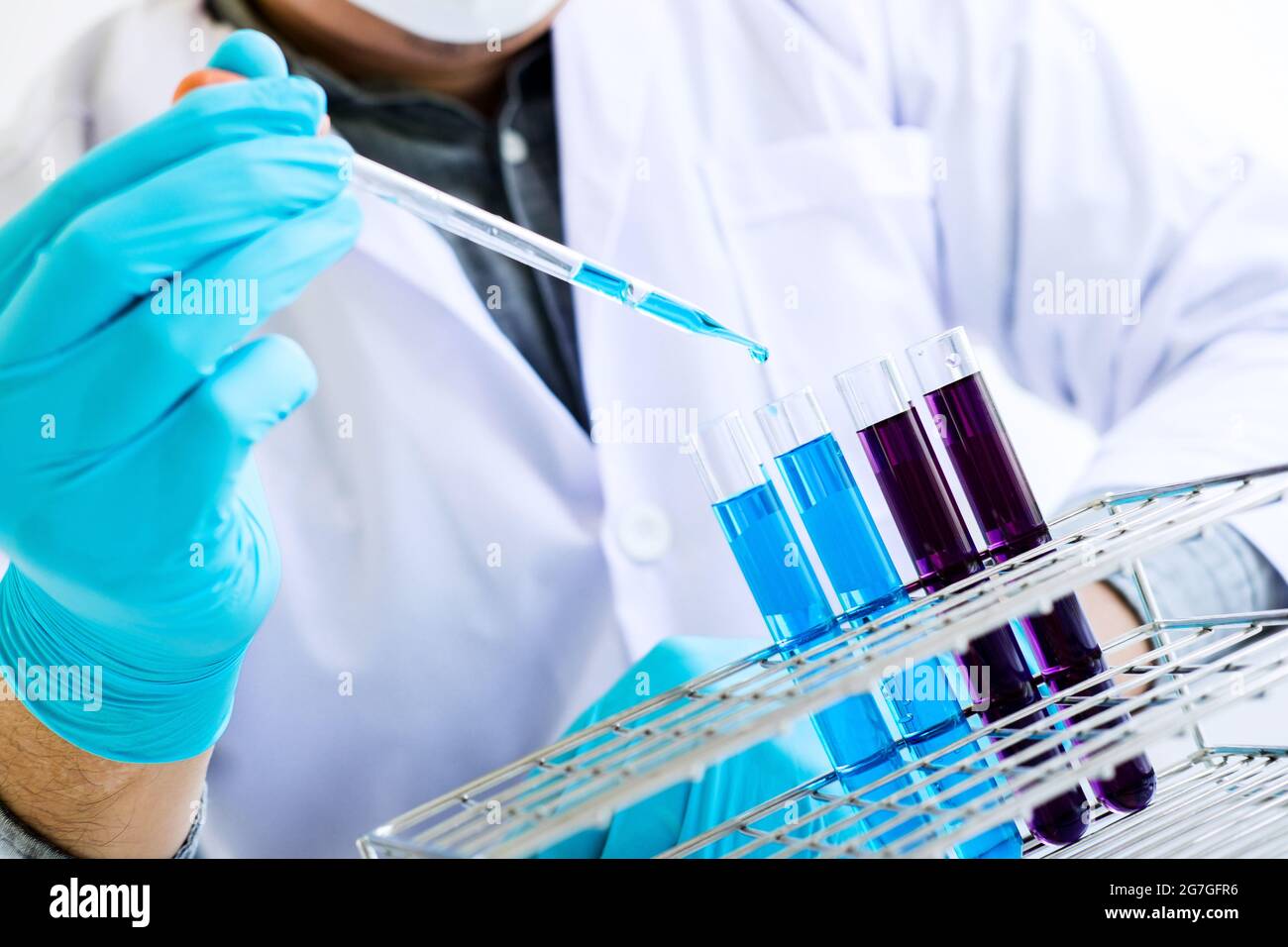 Biochemistry laboratory research, Scientist or medical in lab coat holding test tube with reagent with drop of color liquid over glass equipment worki Stock Photo