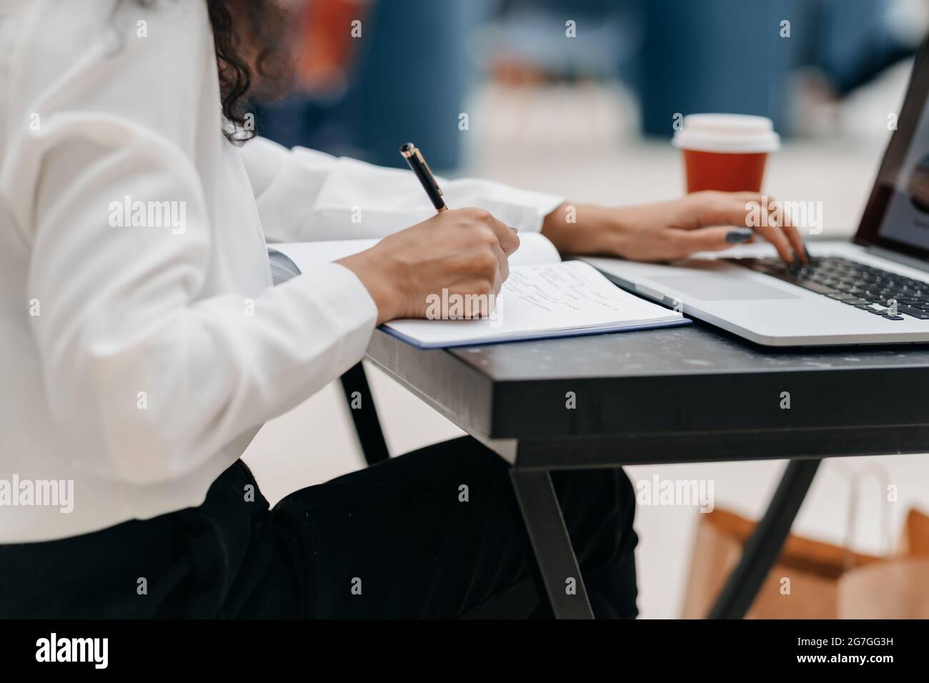 close-up. woman using a laptop and taking notes in a notepad Stock Photo