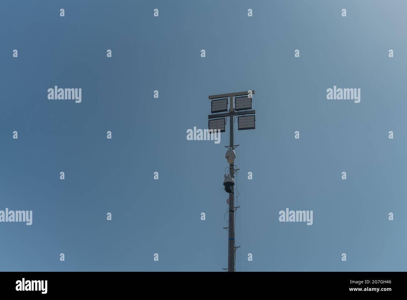 A street pole with surveillance cameras, in a criminal zone, and night lighting lamps. Against the blue sky. Stock Photo