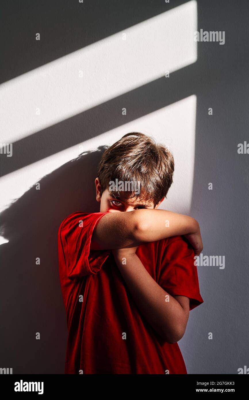 Upset unrecognizable boy covering face with hands and crying while ...