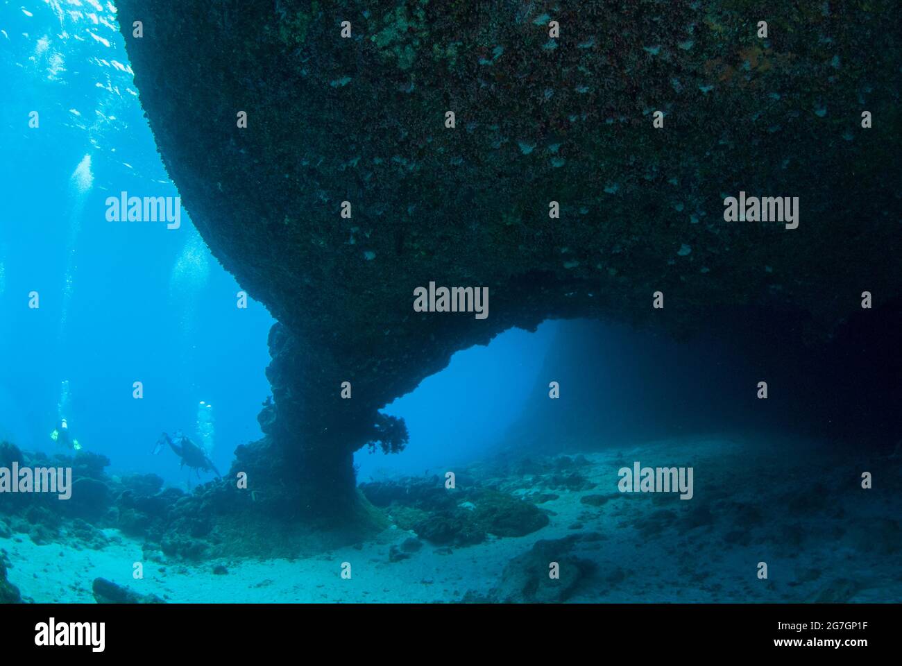 Divers by passageway in cave, West White Beach Cave dive site
