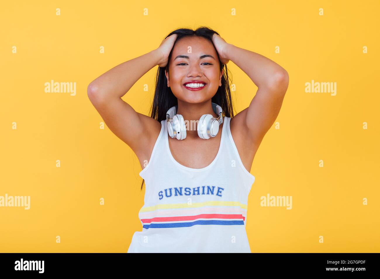 Delighted Asian female standing on yellow background in studio while ...