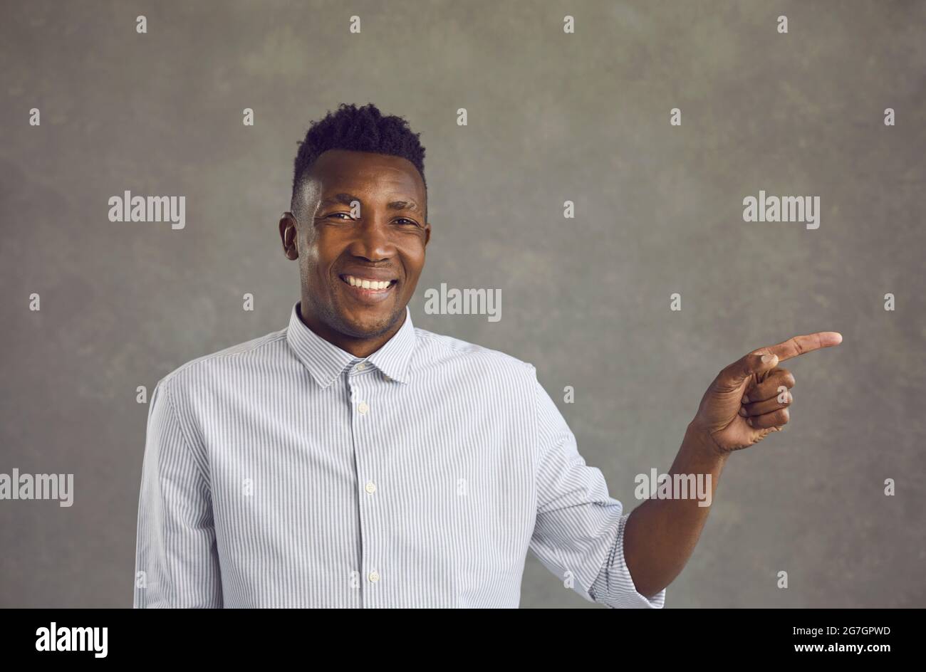 Portrait of happy handsome young black man smiling and pointing away with his finger Stock Photo