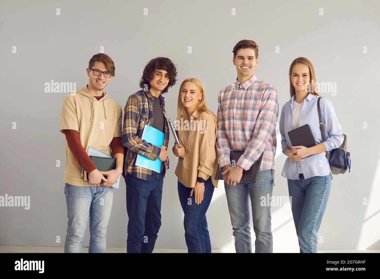 Happily smiling teenage students group portrait isolated on grey background Stock Photo