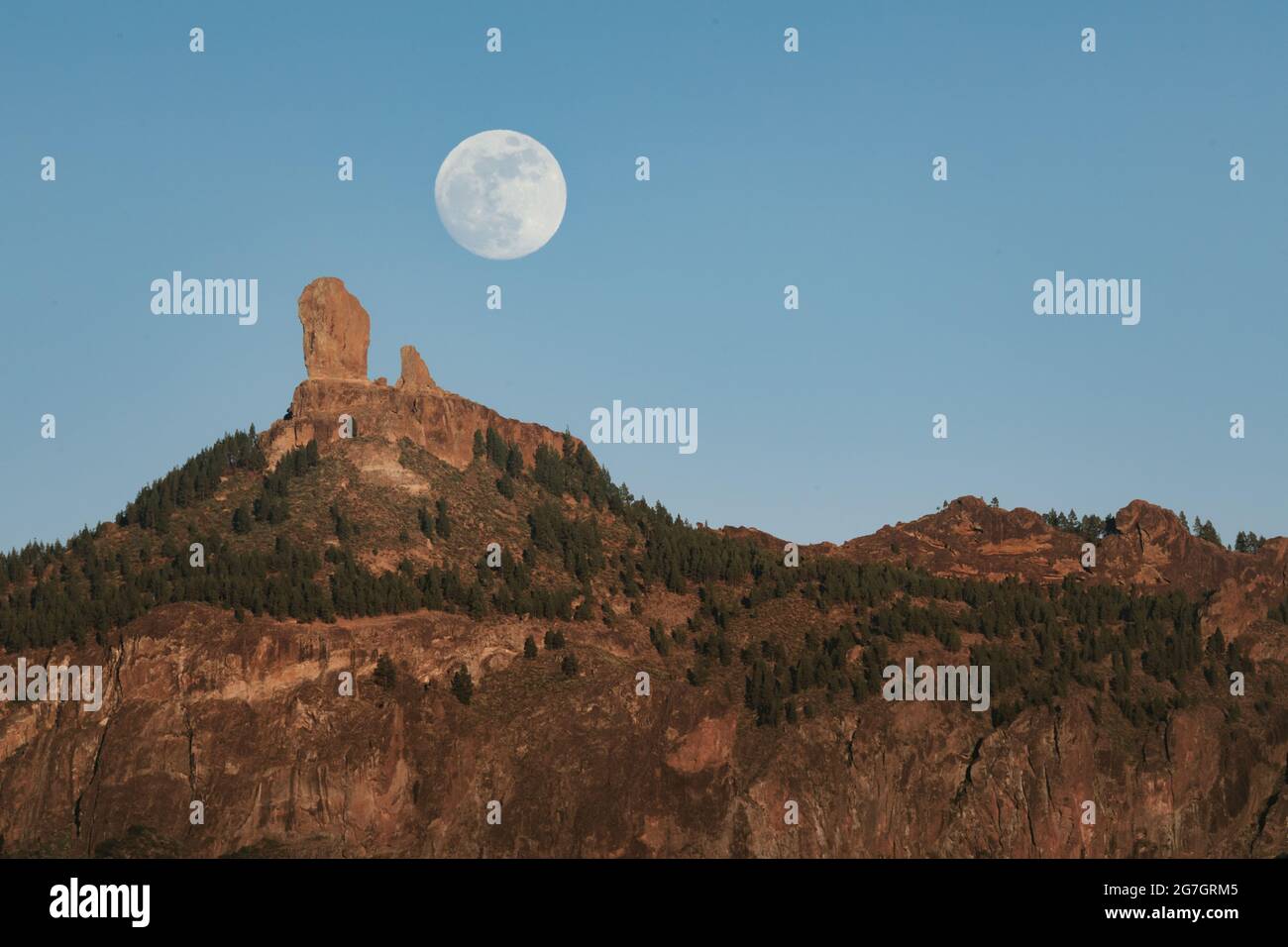 Spectacular landscape with large full moon in blue sky over rocky ...