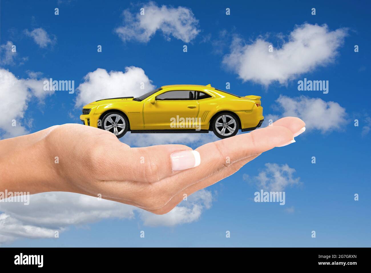 woman's hand with a yellow model car Stock Photo