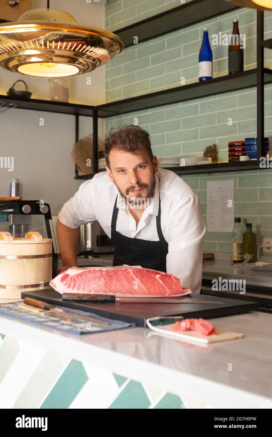 Male sushi chef standing on table in Asian restaurant with Raw fish fillet  placed on cutting board Stock Photo - Alamy