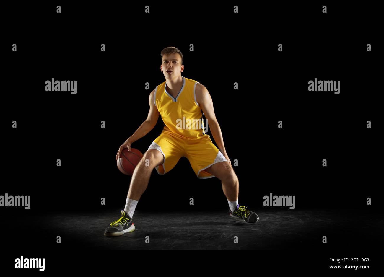 Basketball player with a ball in action and motion isolated on dark black studio background. Advertising concept. Strong Caucasian athlete practicing Stock Photo