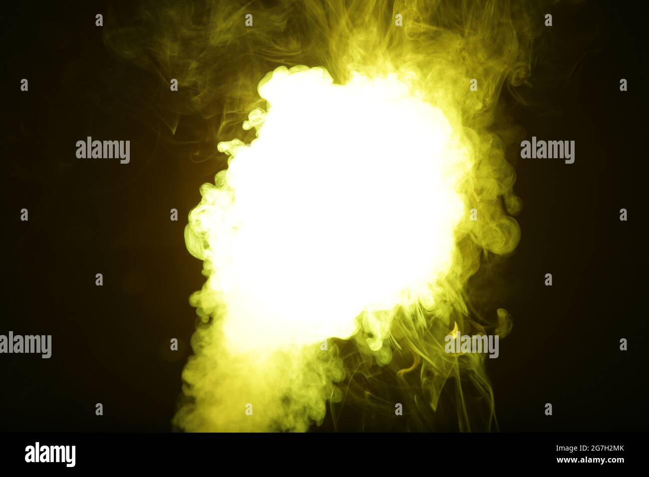 Artificial yellow light illuminates smoke on dark background Stock