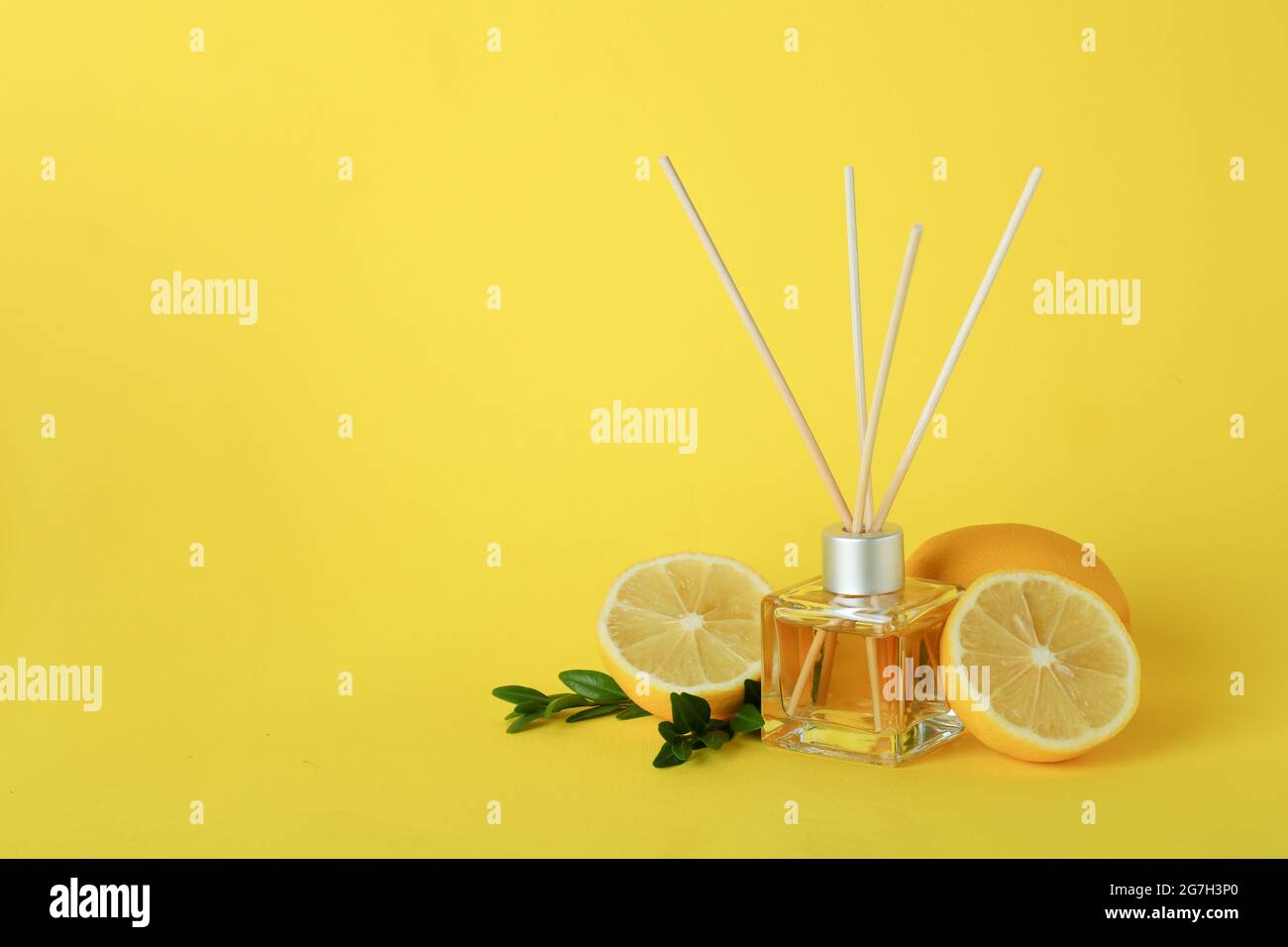 Diffuser, lemons and leaves on yellow background Stock Photo