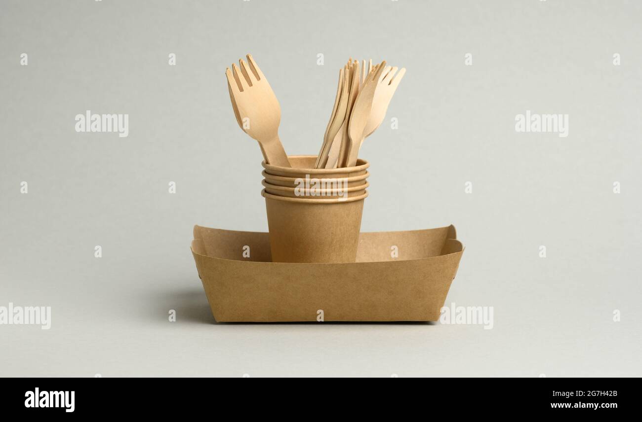 disposable brown paper cups, rectangular plates and wooden forks on a ...