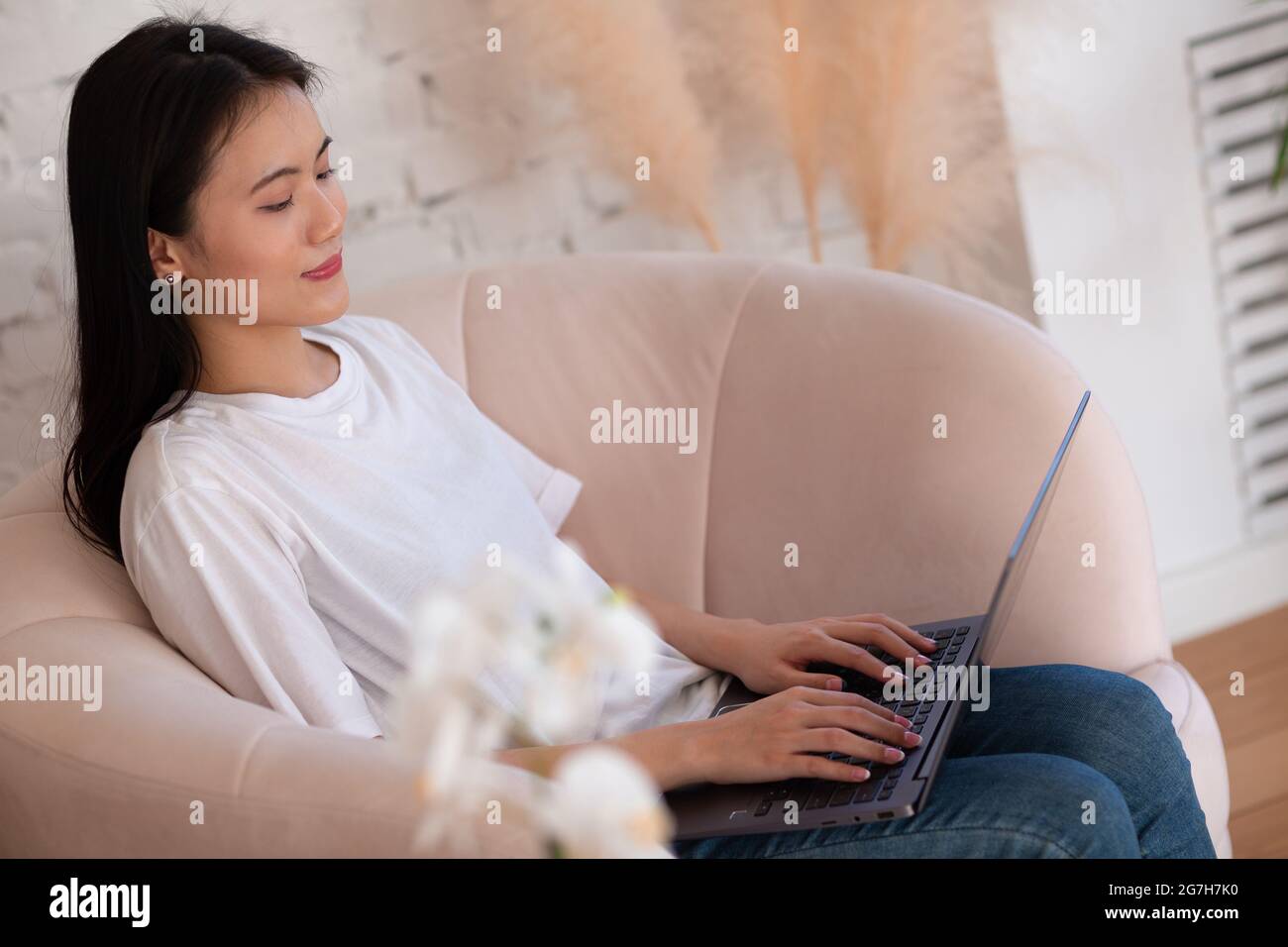 Portrait of asian woman enjoying using laptop at apartment interior indoor living room. Video call vlogger webinar stream concept Stock Photo
