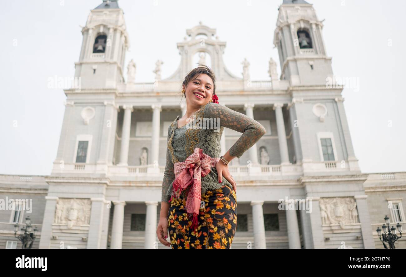 young happy Indonesian woman from Bali having vacation in Europe - attractive and cheerful Balinese tourist girl in traditional outfit touring in the Stock Photo