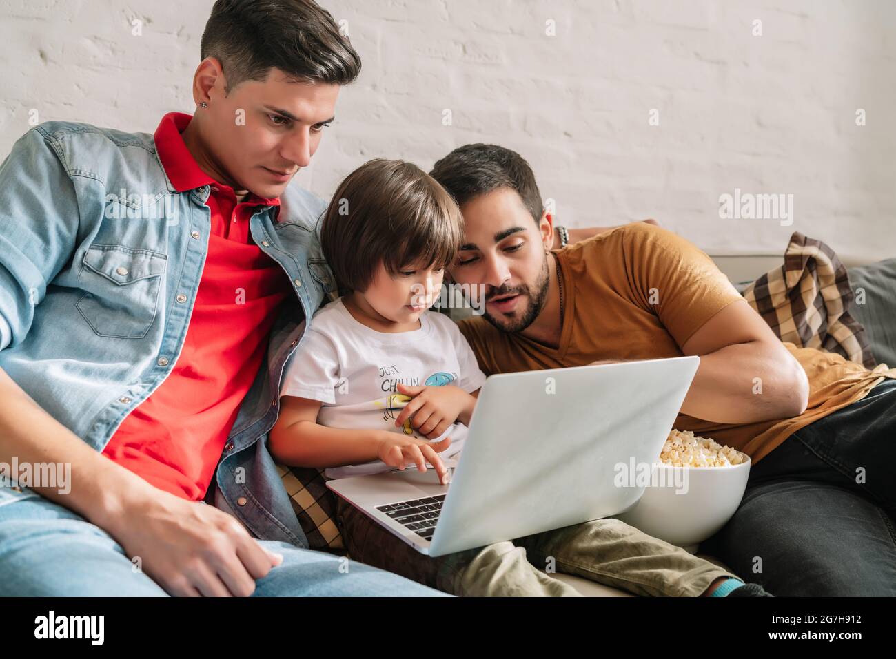Gay couple watching movies with their son at home. Stock Photo