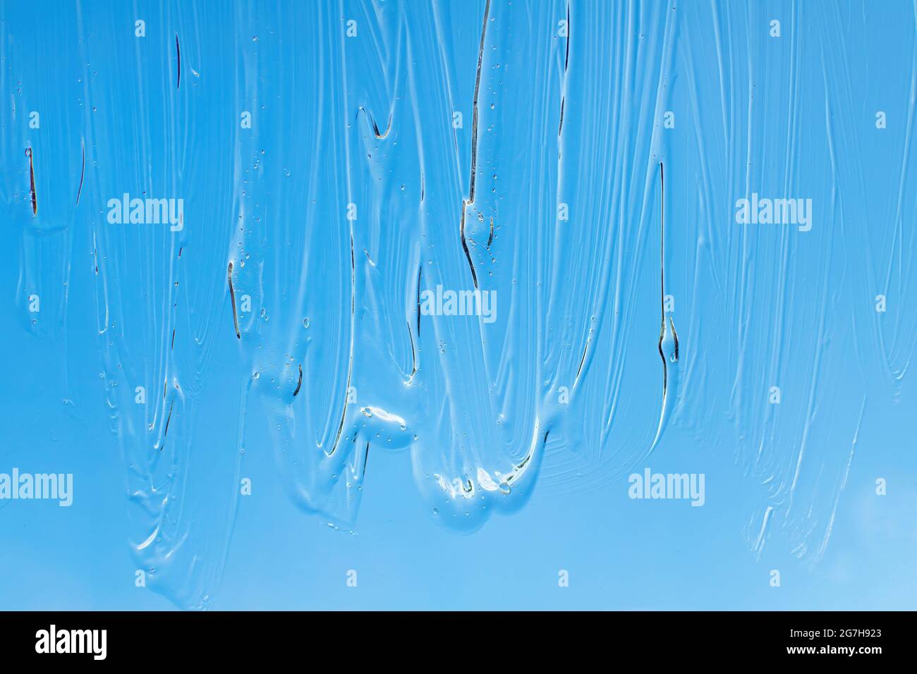 Liquid cosmetic gel on blue background. Gel cream or hand antibacterial gel. Blue texture. Stock Photo
