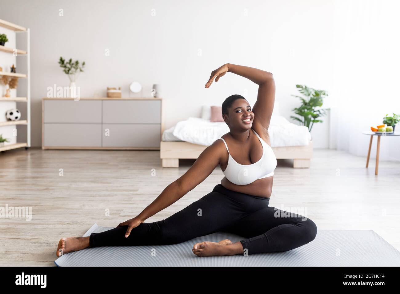 Full length of overweight black lady stretching her body, bending aside on yoga  mat, leading active lifestyle during covid lockdown at home. Curvy you Stock  Photo - Alamy