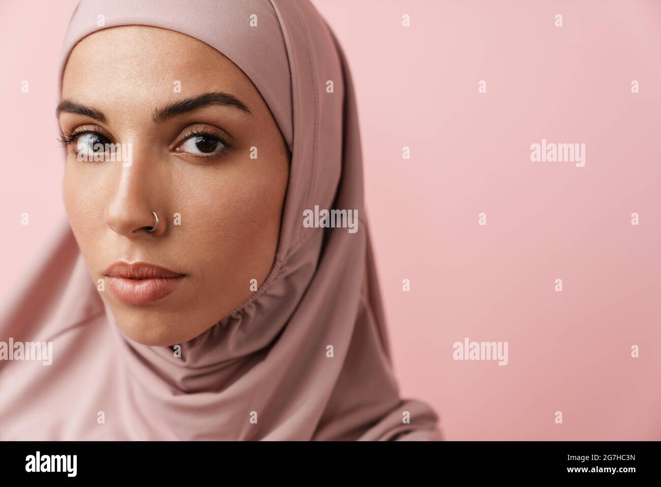 A close-up view of the confident muslim woman in pink hijab looking at ...