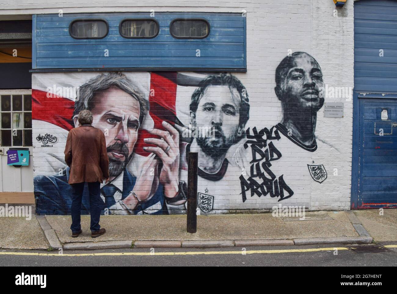 London, UK. 14th July, 2021. A man admires the mural of England football manager Gareth Southgate and players Harry Kane and Raheem Sterling, with the words 'You Did Us Proud', is seen on a wall at Vinegar Yard in London. The mural was painted by MurWalls following the England football team's achievement of making it to the final of Euro 2020. Credit: SOPA Images Limited/Alamy Live News Stock Photo