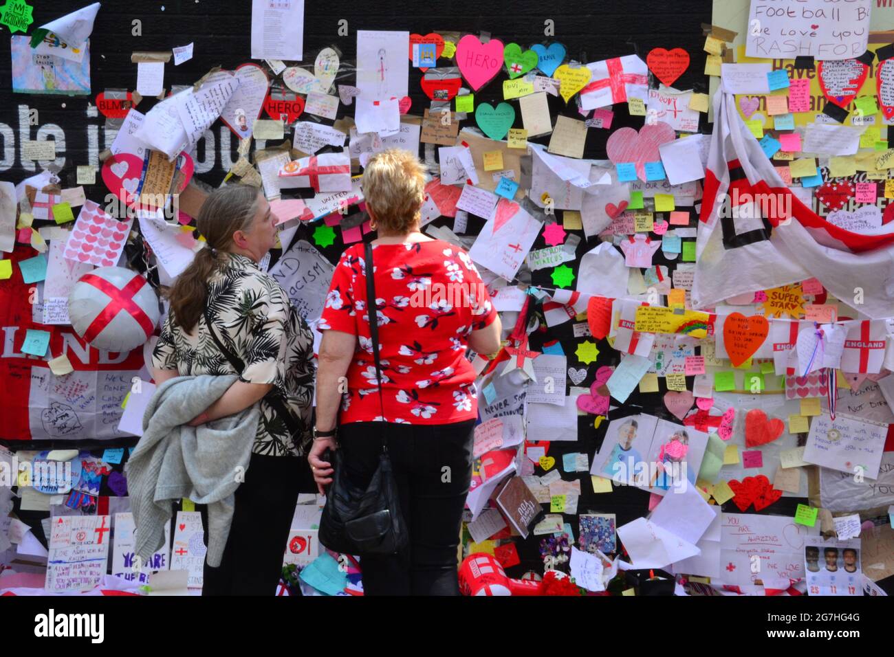 People leave flowers and hundreds of supportive notes, pictures, flags and anti racist messages on the giant  Manchester United player  Marcus Rashford mural in Withington, Manchester, England, United Kingdom, that was vandalised  with abusive graffiti after England's Euro2020 football loss on July 11th, 2021. The mural was created by French-born street artist Akse P19 on the wall of the Coffee House Cafe on Copson Street. People have left thousands of supportive notes, pictures, flags, flowers  and anti racist messages following the defacement. Stock Photo