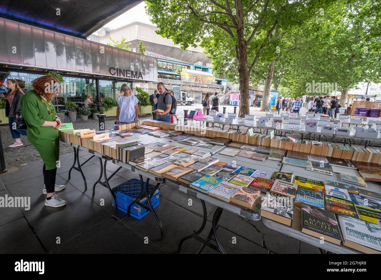 Perusing books at an open air bookstall under Waterloo Bridge next to the South Bank centre on the Thames riverside walk in London near Waterloo Stock Photo