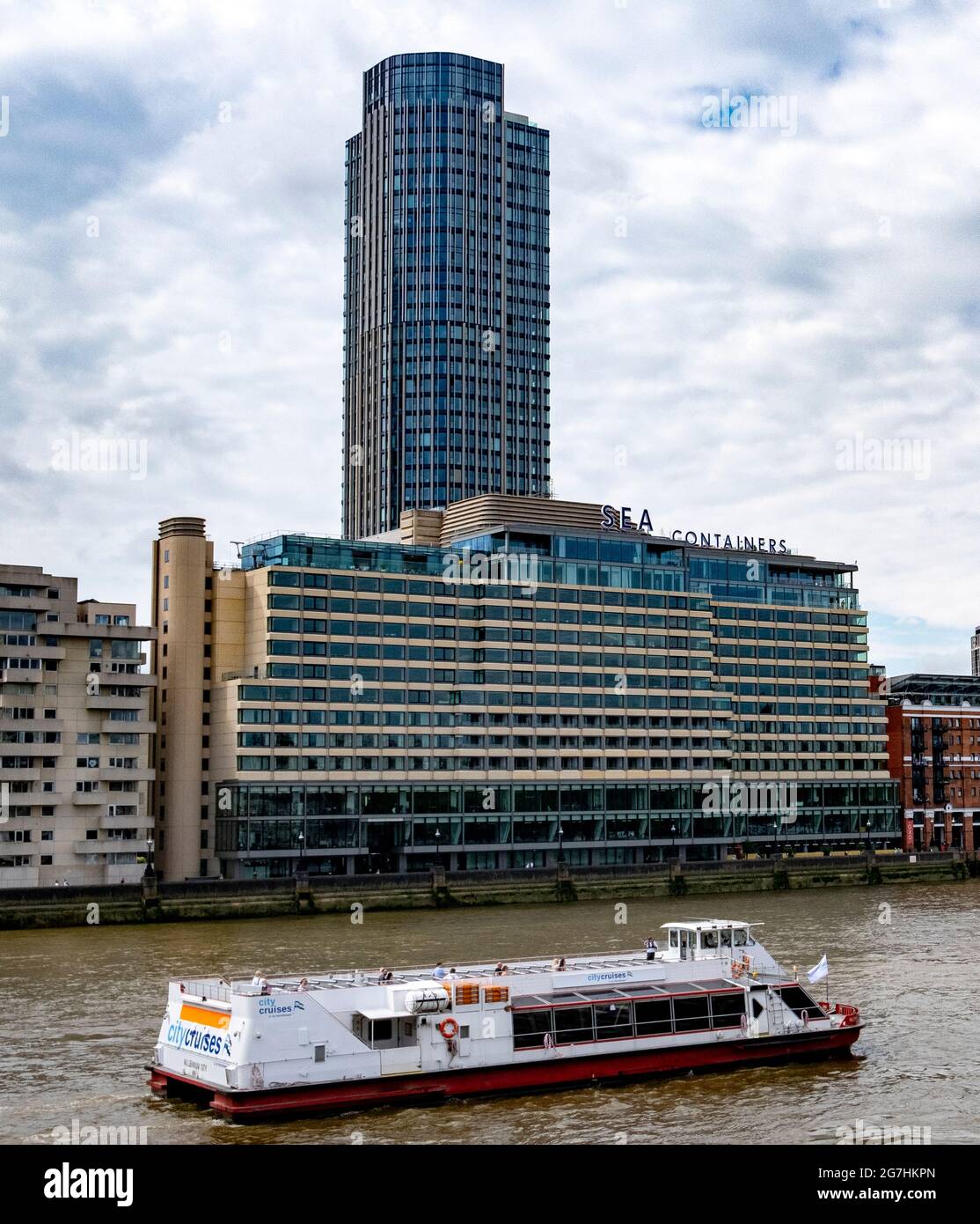 A sightseeing cruise on the River Thames in London passes Sea Containers House with South Bank Tower on the river bank Stock Photo